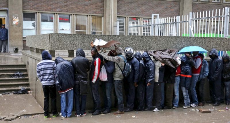 Asylum seekers queue outside the Customs House building in Cape Town. As of May 2020, it was estimated that there were 188,296 active asylum files and 80,752 recognised refugees in South Africa. (Photo by Gallo Images / Nardus Engelbrecht)